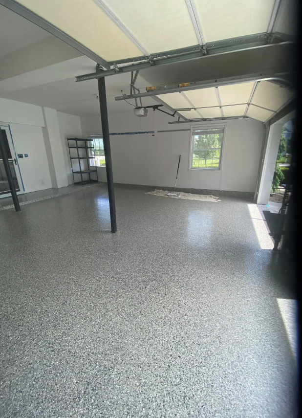 Bright empty room with polished floors, kitchen counter, and sunlit French doors.