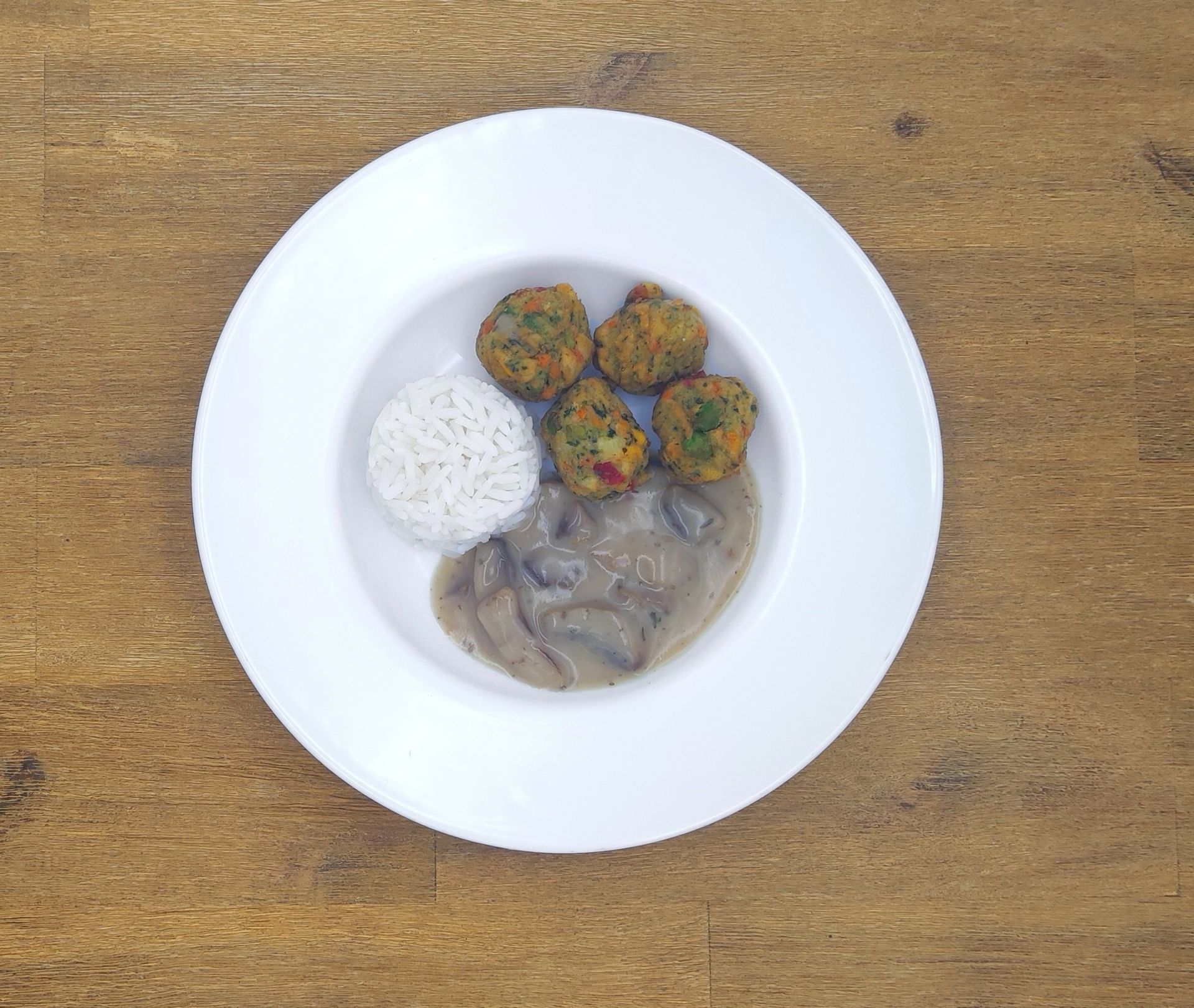 Weiße Schüssel mit Linsensuppe und Brot auf einer Holzoberfläche.