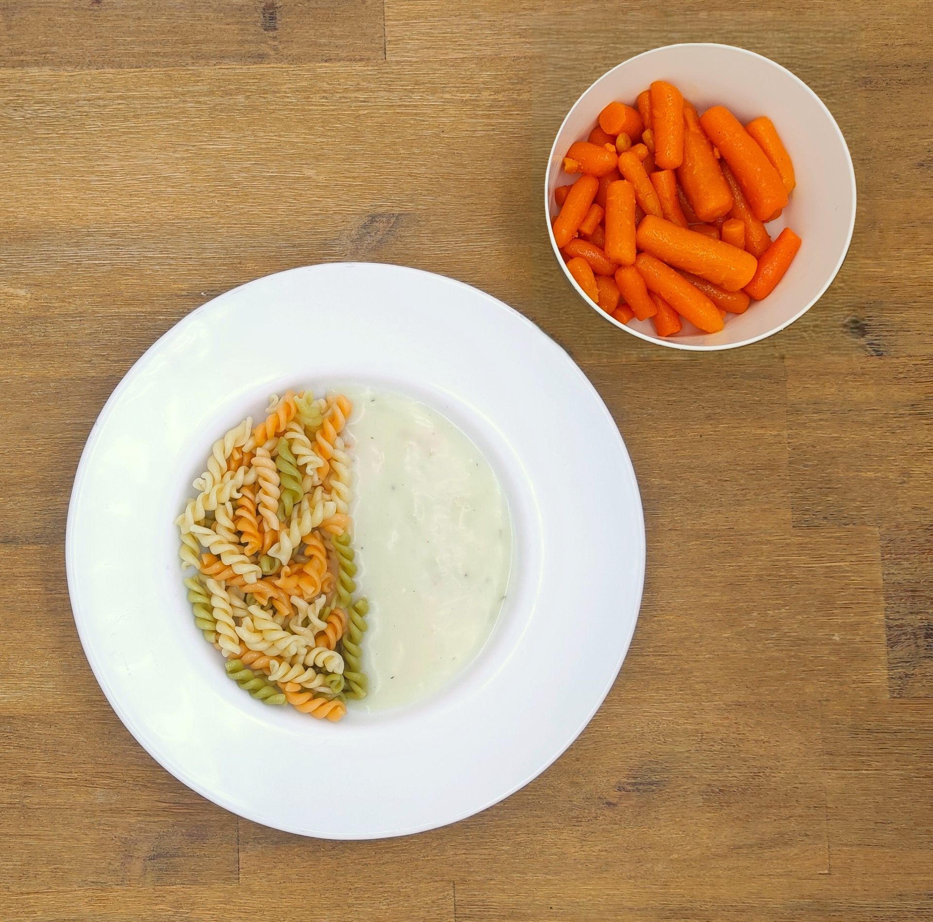 Weißer Teller mit Farfalle-Nudeln und Orangensauce, bestreut mit geriebenem Käse.