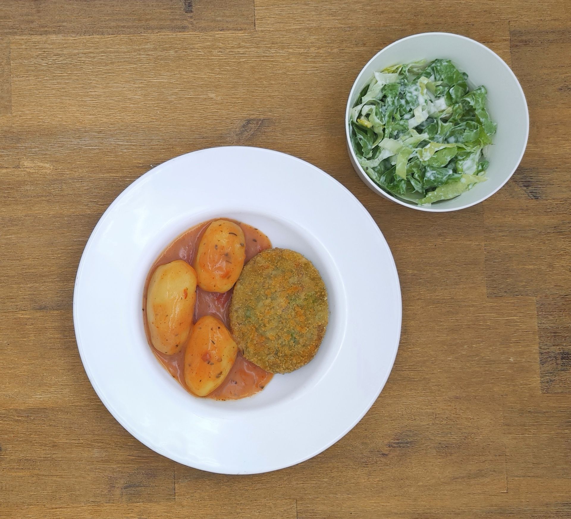 Weiße Schüssel mit Linsensuppe und Brot auf einer Holzoberfläche.