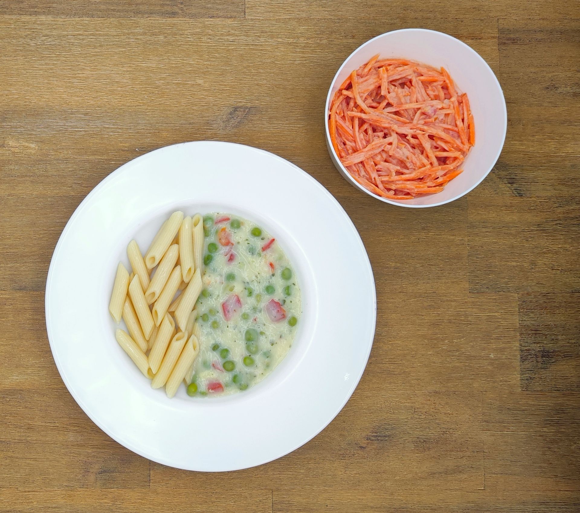 Weißer Teller mit Farfalle-Nudeln und Orangensauce, bestreut mit geriebenem Käse.