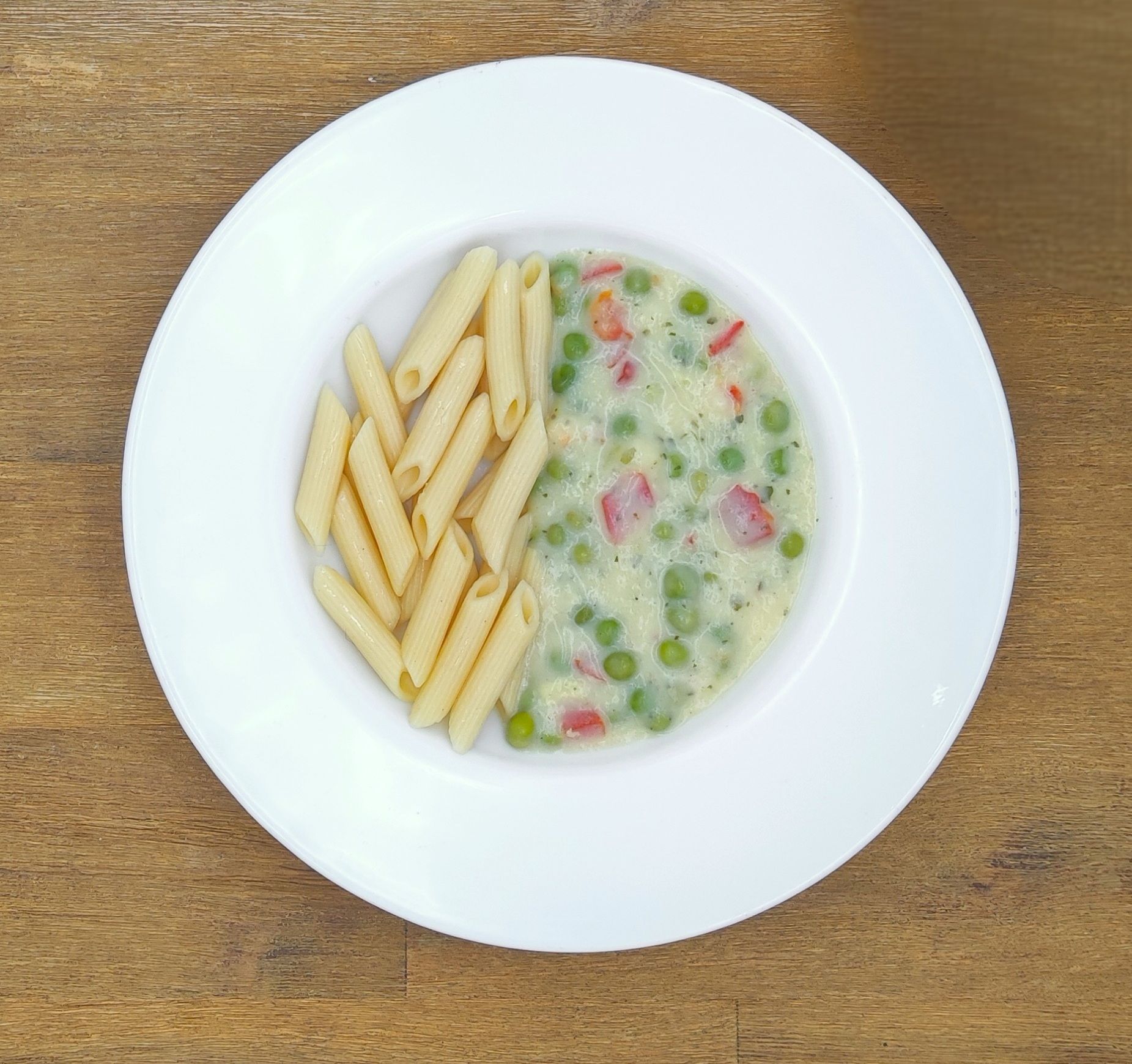 Weißer Teller mit Farfalle-Nudeln und Orangensauce, bestreut mit geriebenem Käse.