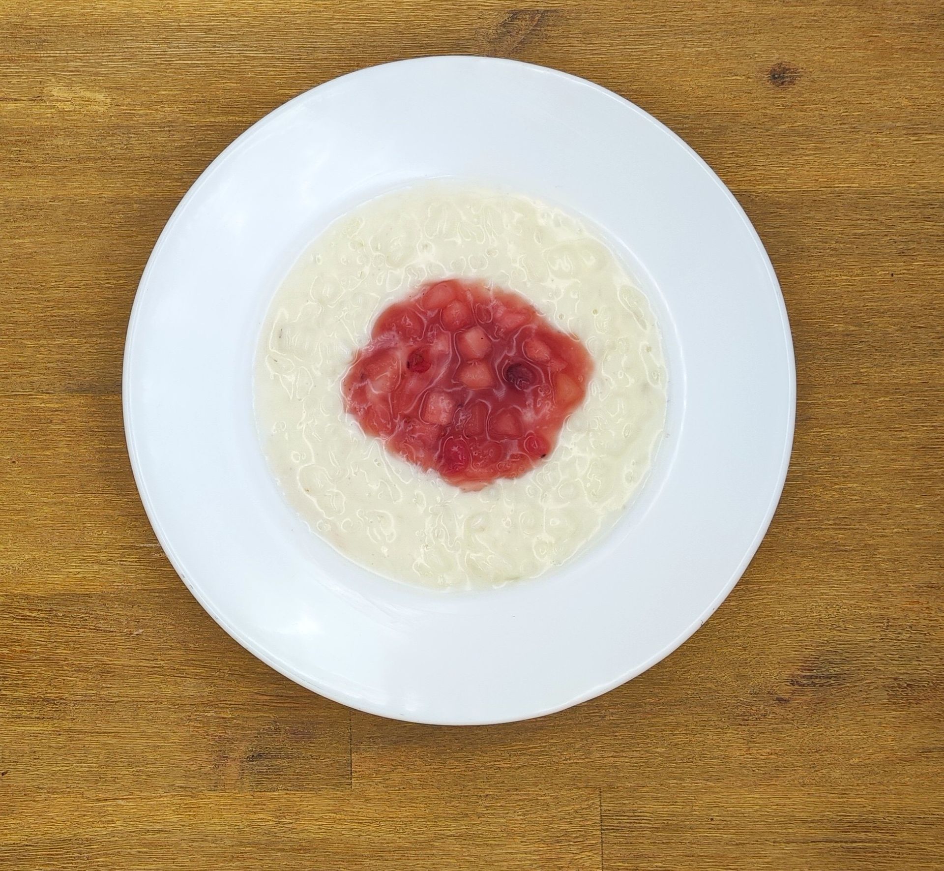 Auf einem weißen Teller mit Apfelmus lagen Crêpes auf einem Holztisch.