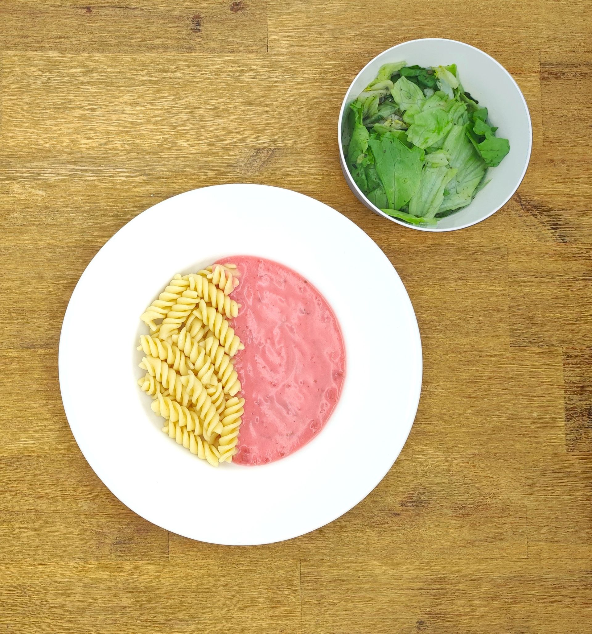 Weiße Schüssel mit Linsensuppe und Brot auf einer Holzoberfläche.