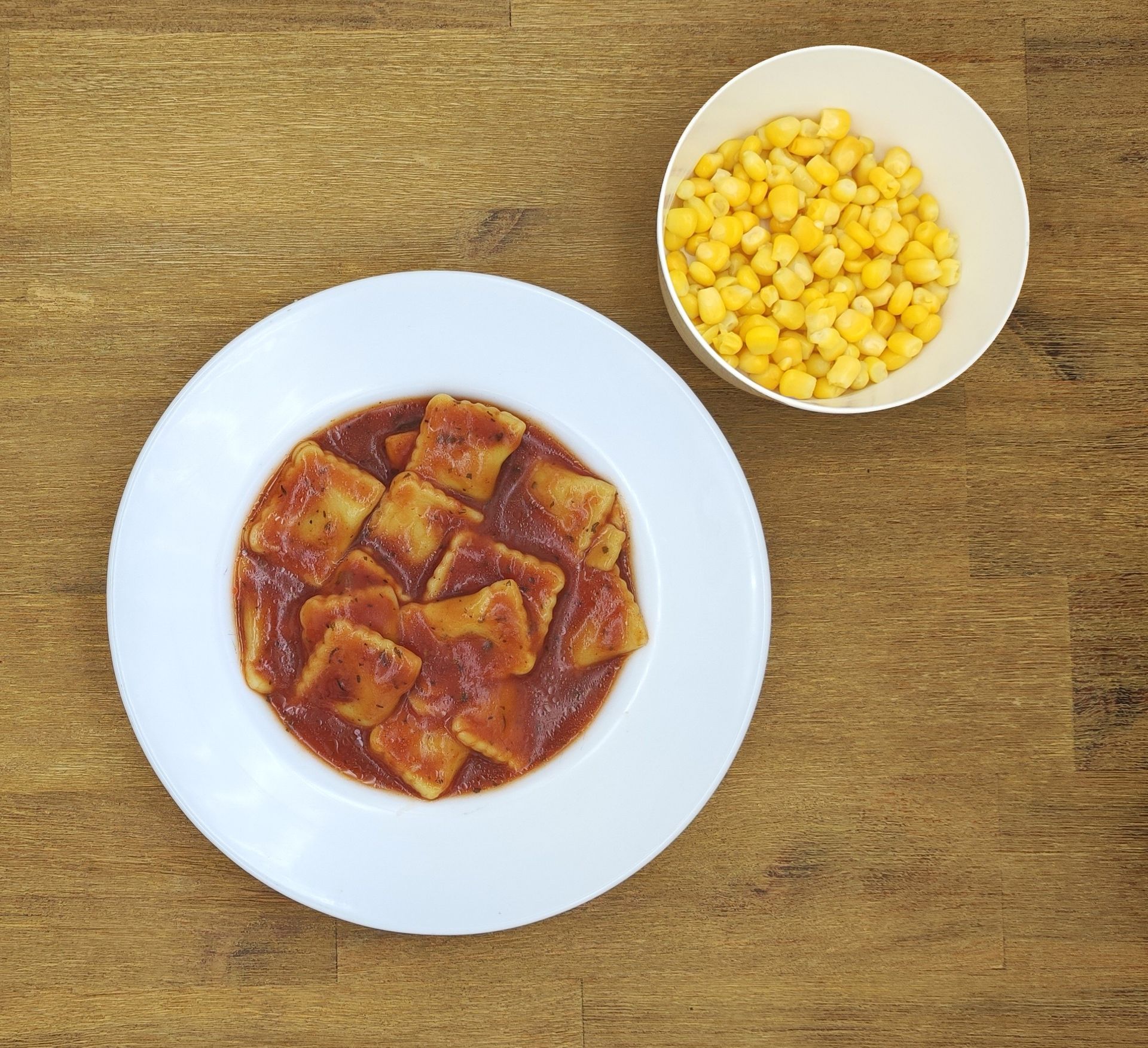Weiße Schüssel mit Linsensuppe und Brot auf einer Holzoberfläche.