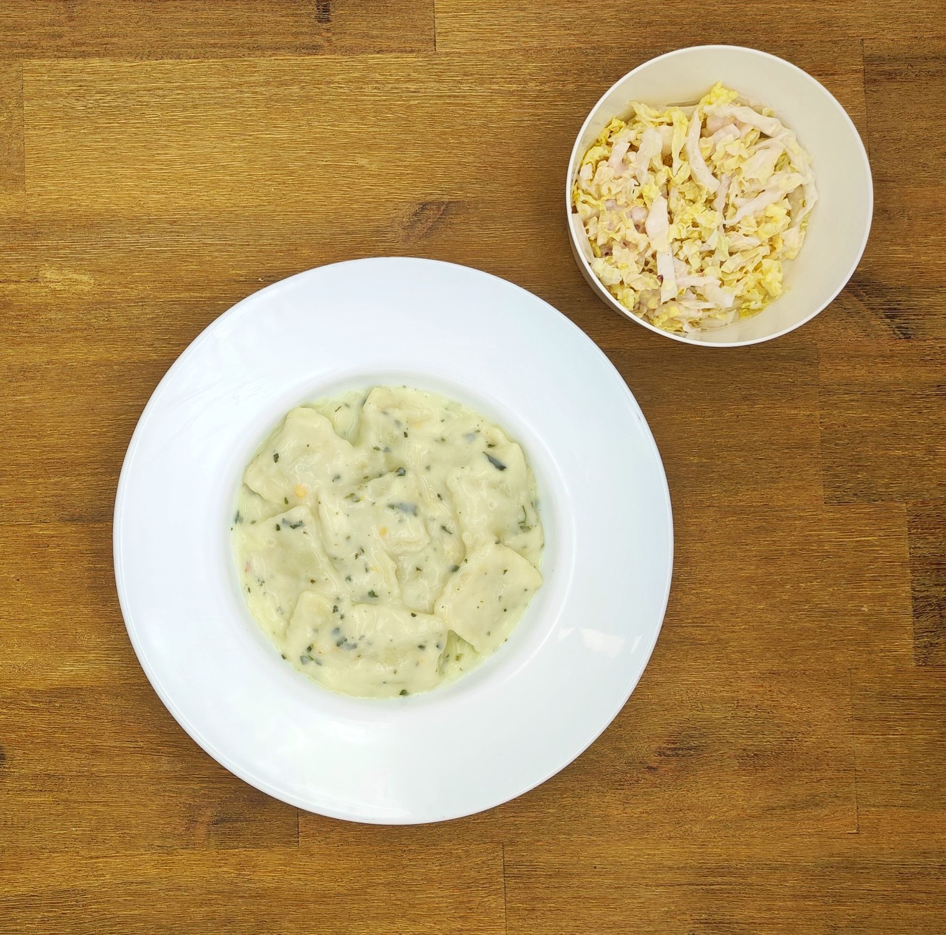 Weiße Schüssel mit Linsensuppe und Brot auf einer Holzoberfläche.
