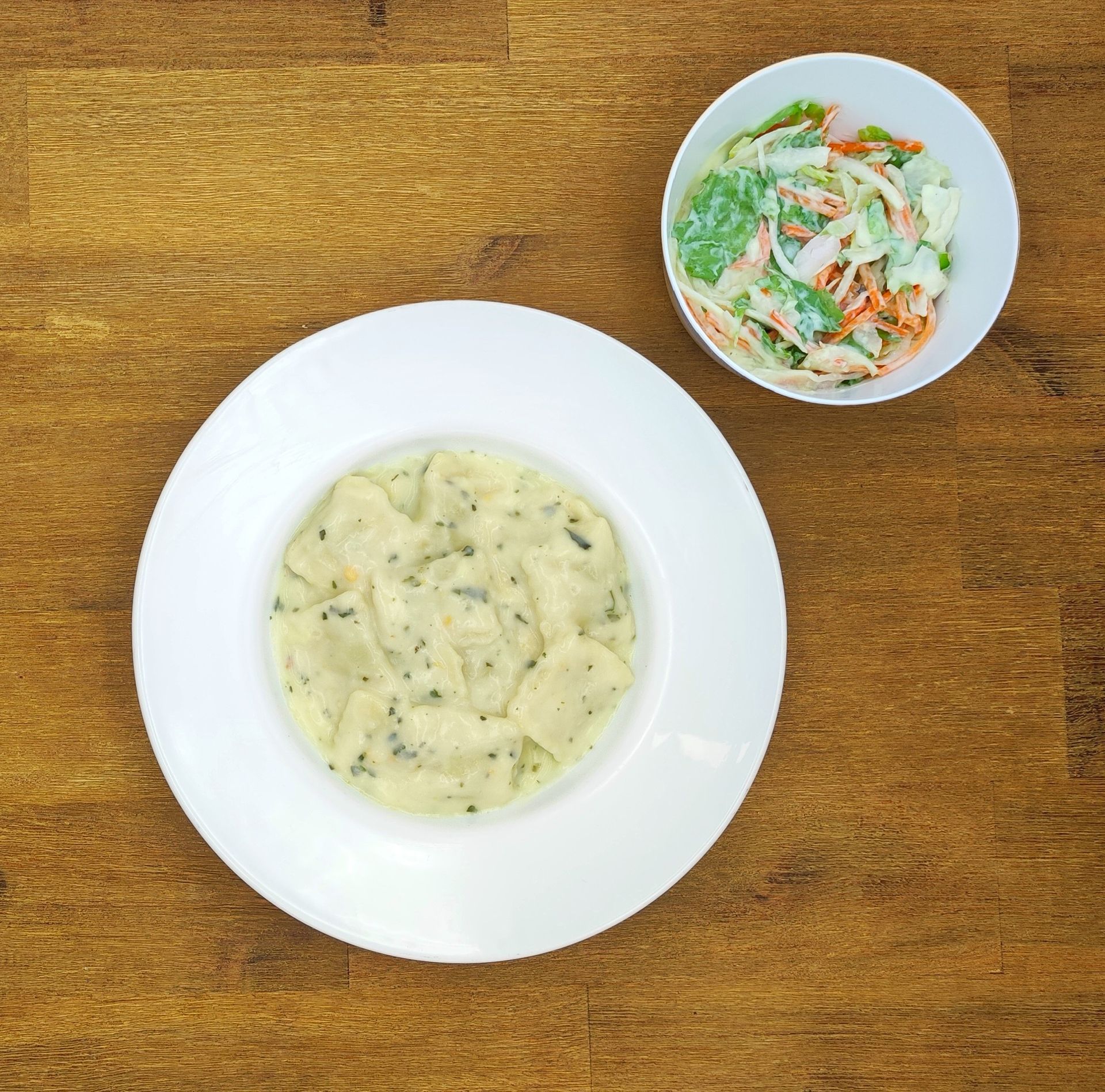 Weiße Schüssel mit Linsensuppe und Brot auf einer Holzoberfläche.