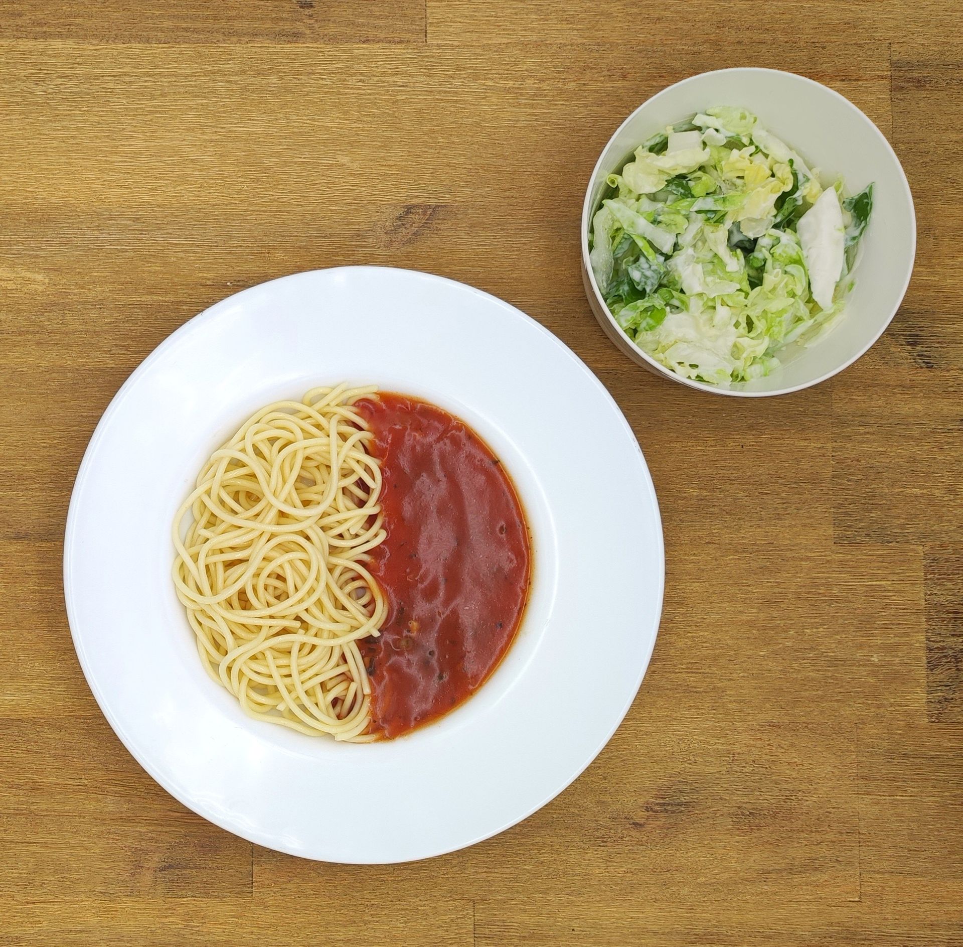 Weiße Schüssel mit Linsensuppe und Brot auf einer Holzoberfläche.