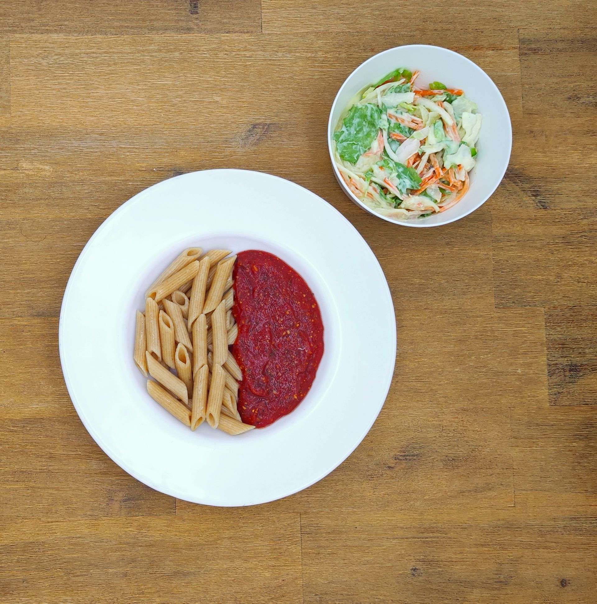 Weiße Schüssel mit Linsensuppe und Brot auf einer Holzoberfläche.