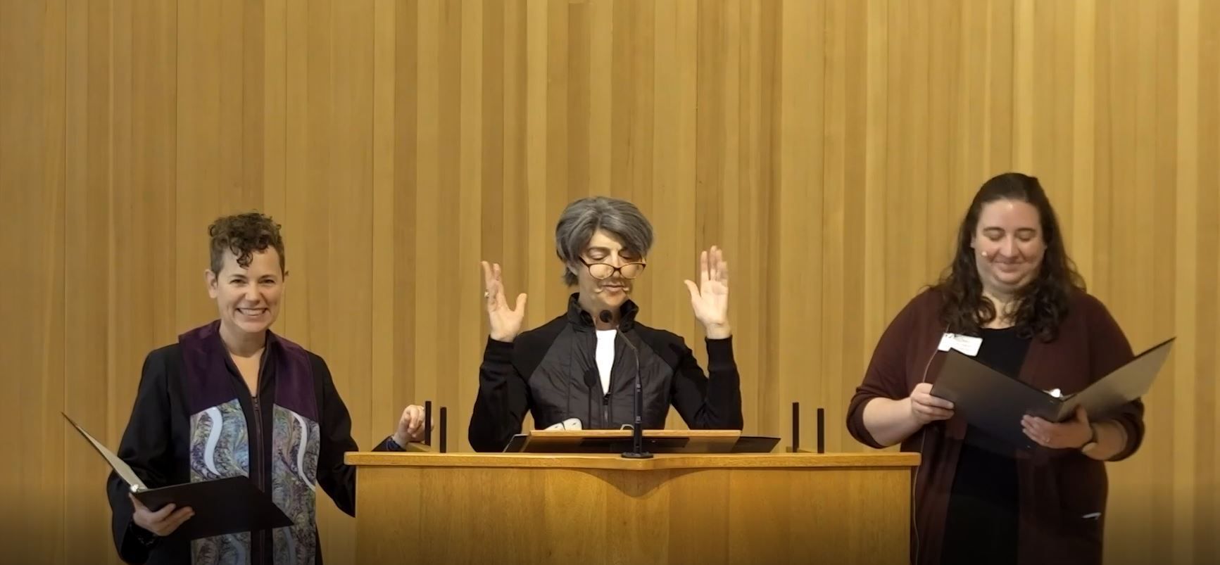 Rev. Beth Chronister stand to the left of the pulpit where Margaret Sutro is speaking.  Director of Religious Education, Aria Curtis stands to the right of Margaret Sutro and the pulpit.