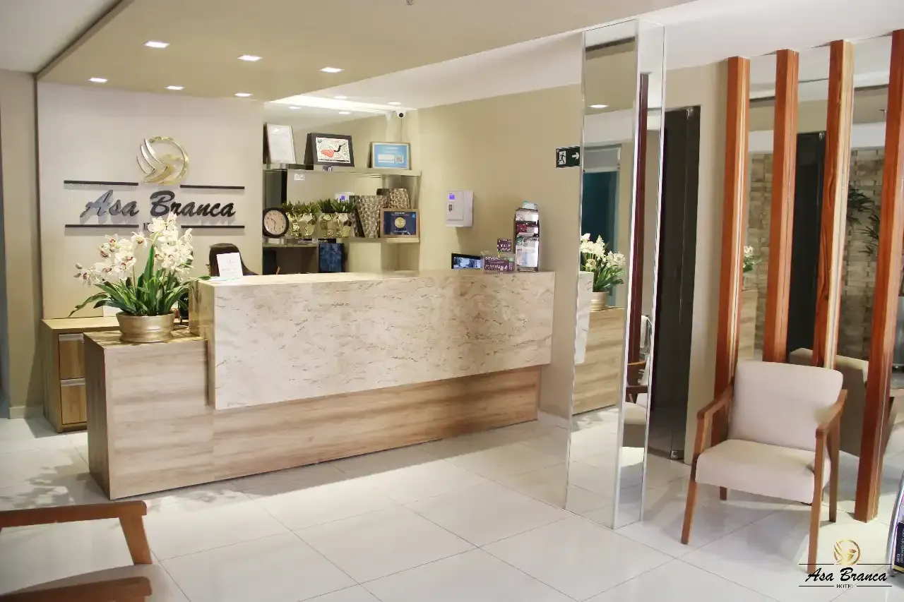 Um lobby de hotel com balcão de recepção e cadeirashotel-asa-branca
