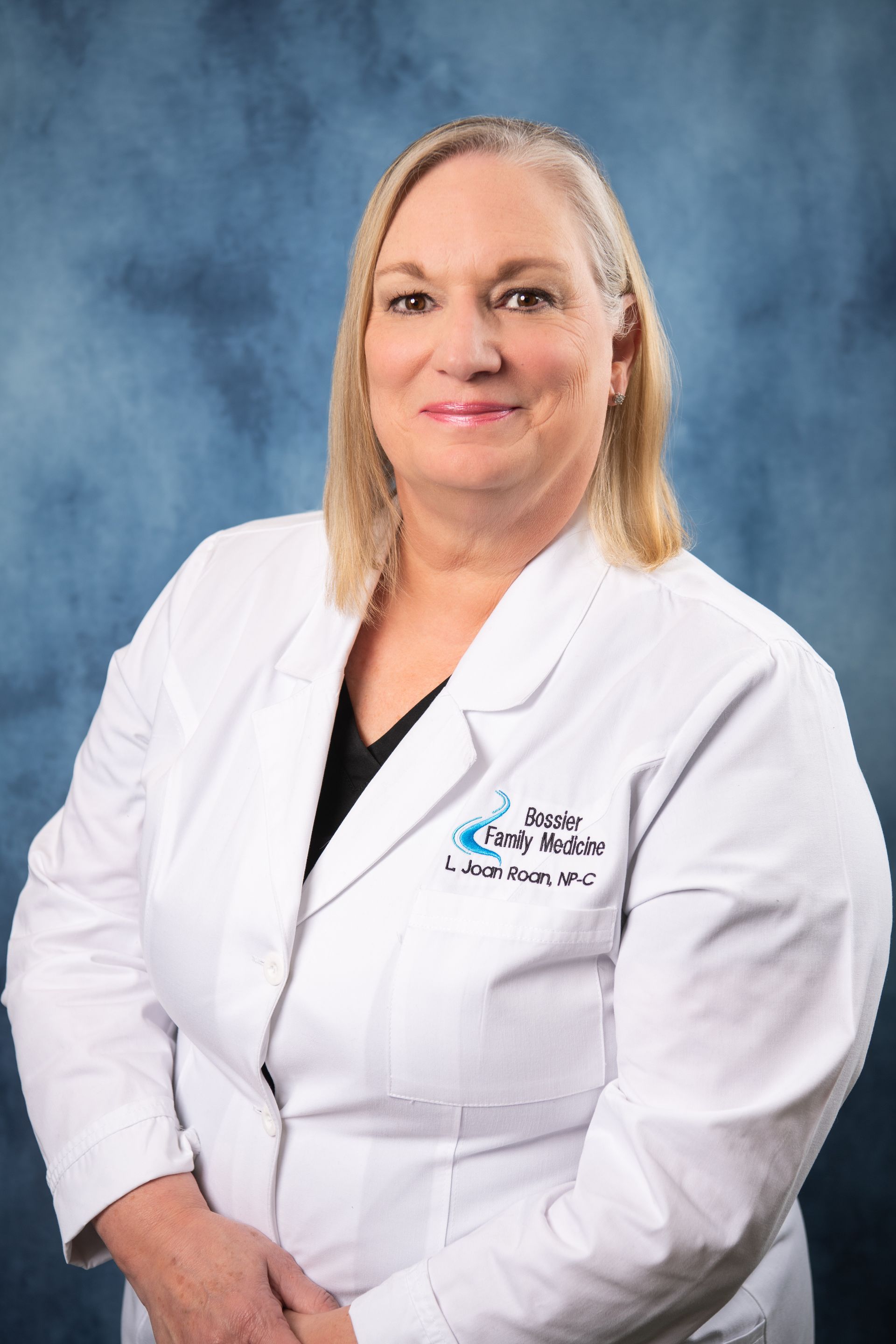 A woman in a white lab coat is smiling for the camera