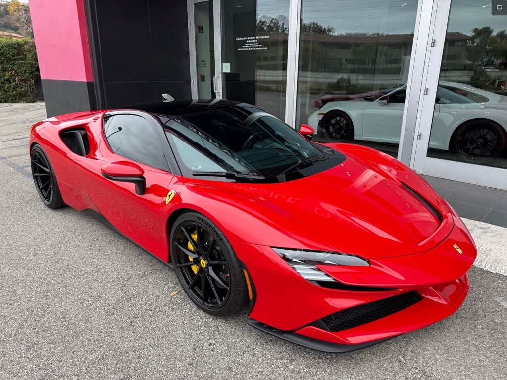 Red Ferrari SF90 sports car parked outside a building, black roof, black wheels with yellow calipers.