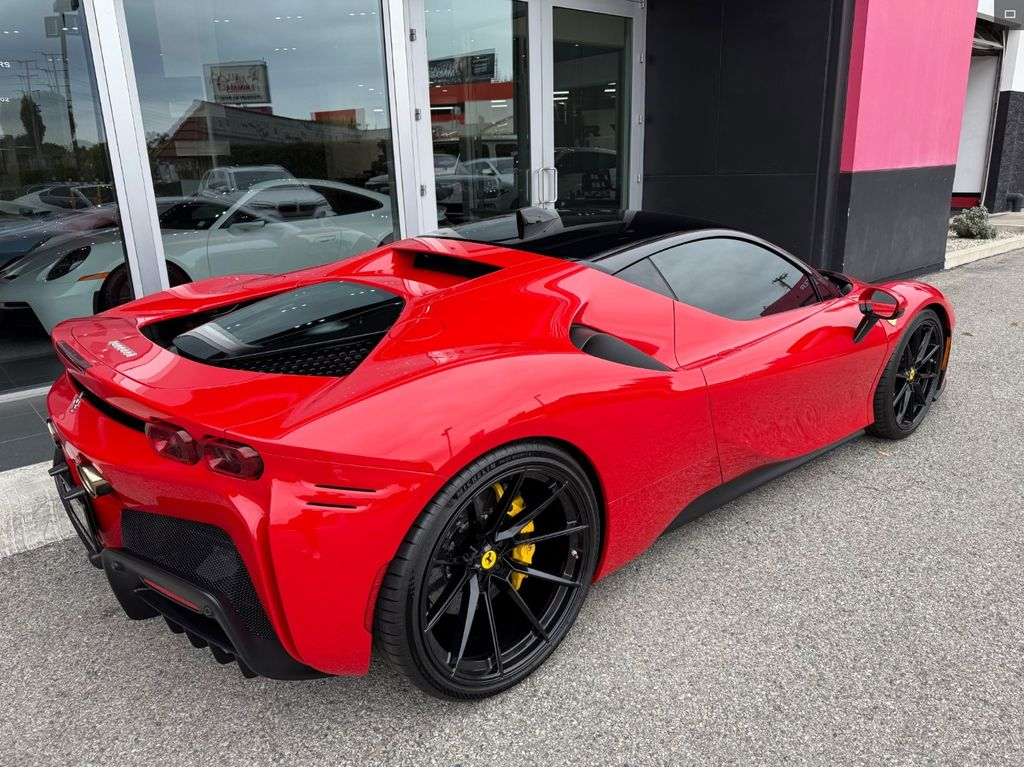 Red sports car with black roof and wheels, parked outside a building with glass windows.