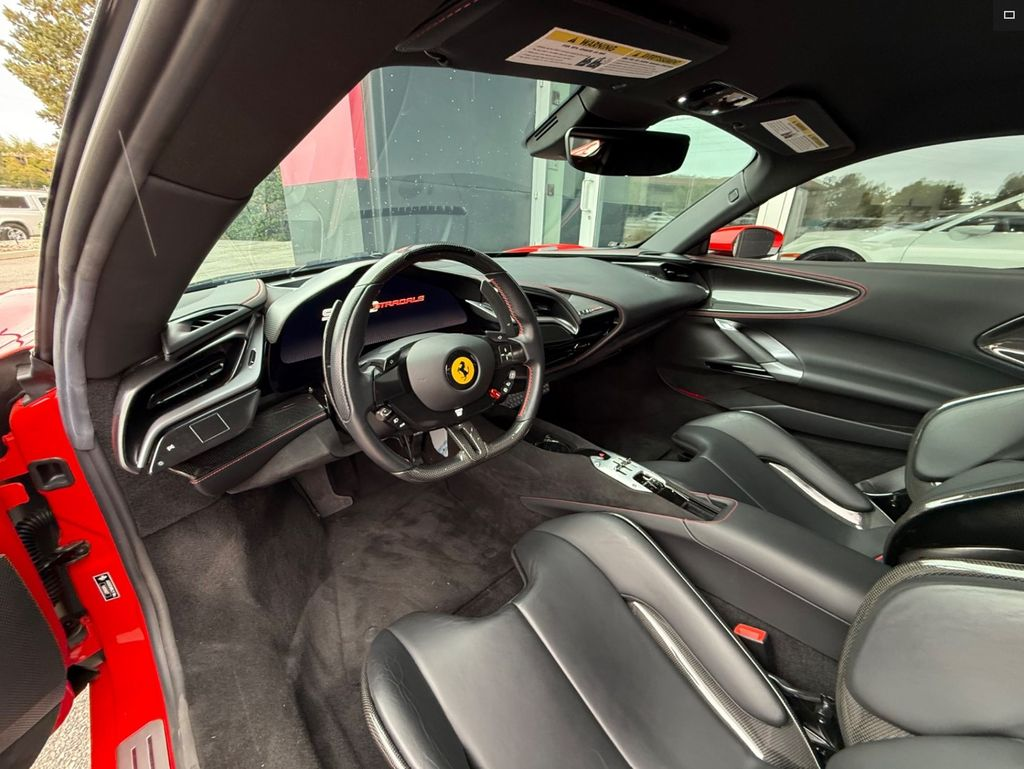 Black interior of a red Ferrari, showing steering wheel and seats.