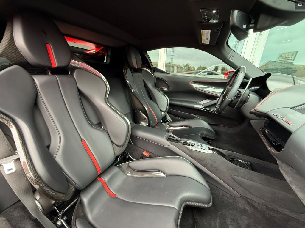 Black car interior with red accents. Leather seats, steering wheel, and dashboard visible.