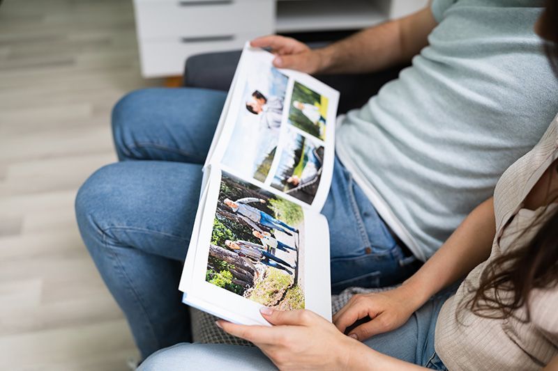 People sitting on a couch looking at a printed photo book