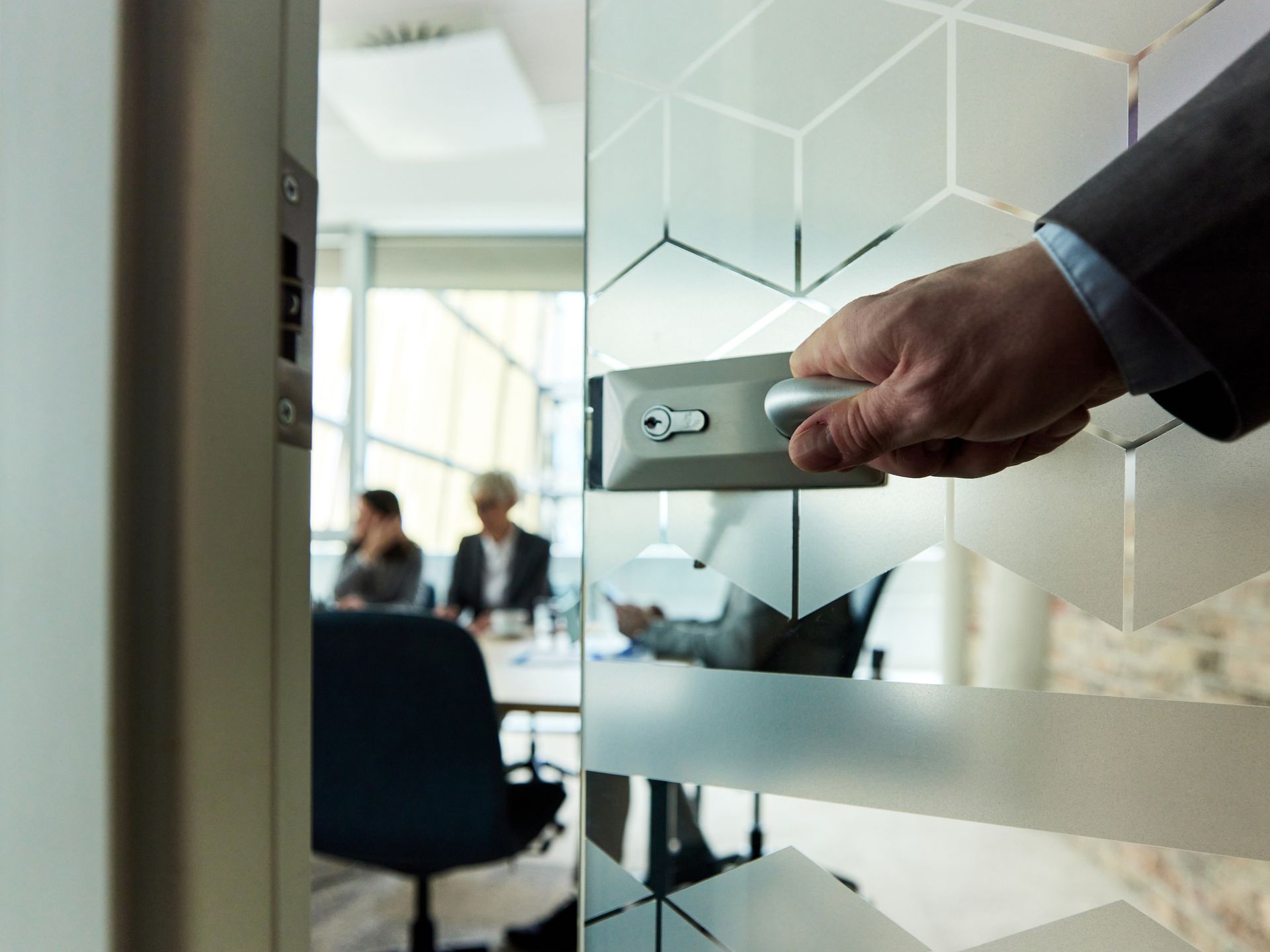 Close-up of the hand of a businessman opening a glass door into a meeting room