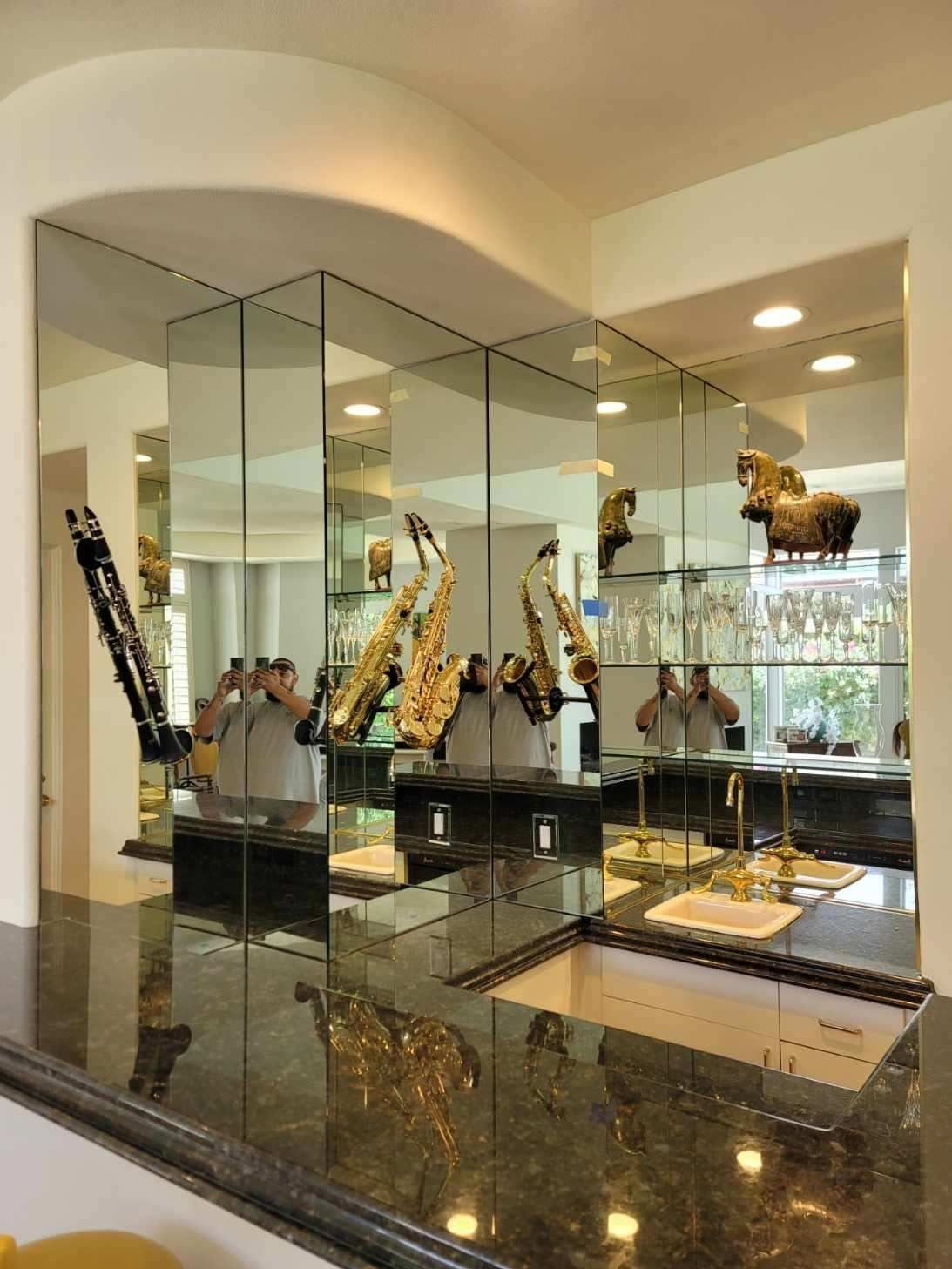 Mirrored kitchen bar with golden saxophones and reflected figures.