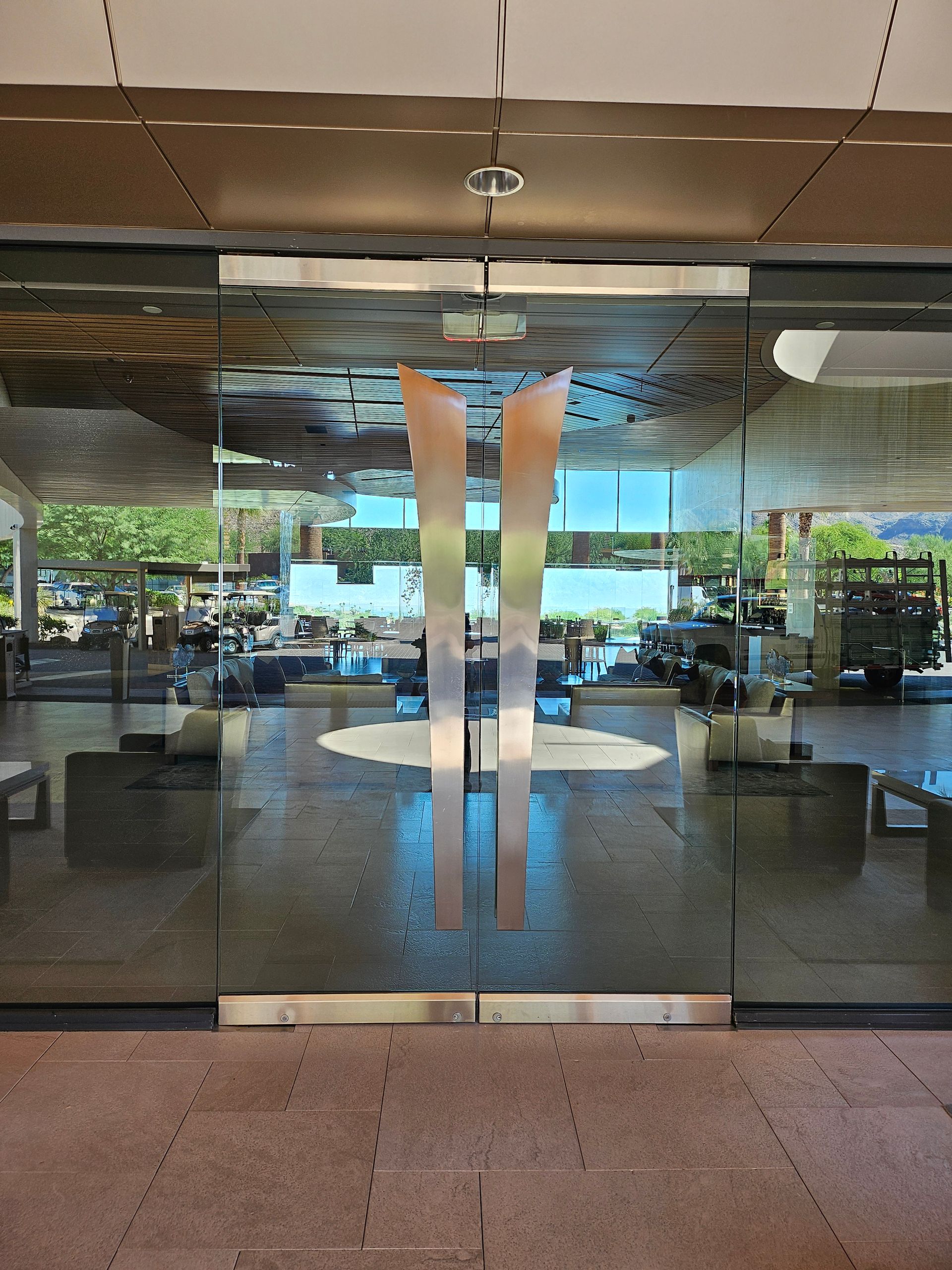 Glass double doors with silver handles, reflecting the interior and exterior of a building.