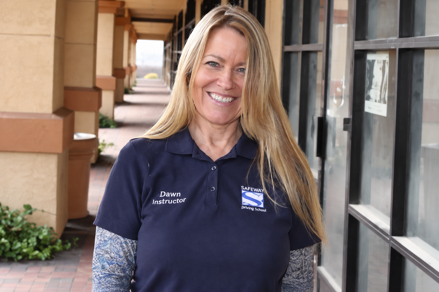 Smiling woman in navy polo standing outdoors by a building with windows and columns