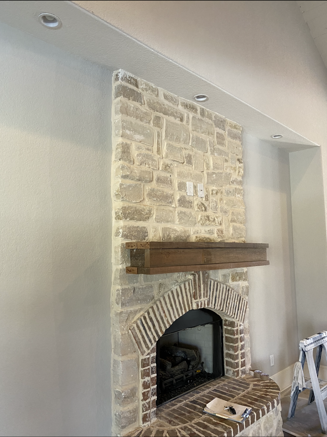 A brick fireplace with a wooden mantle in a living room.