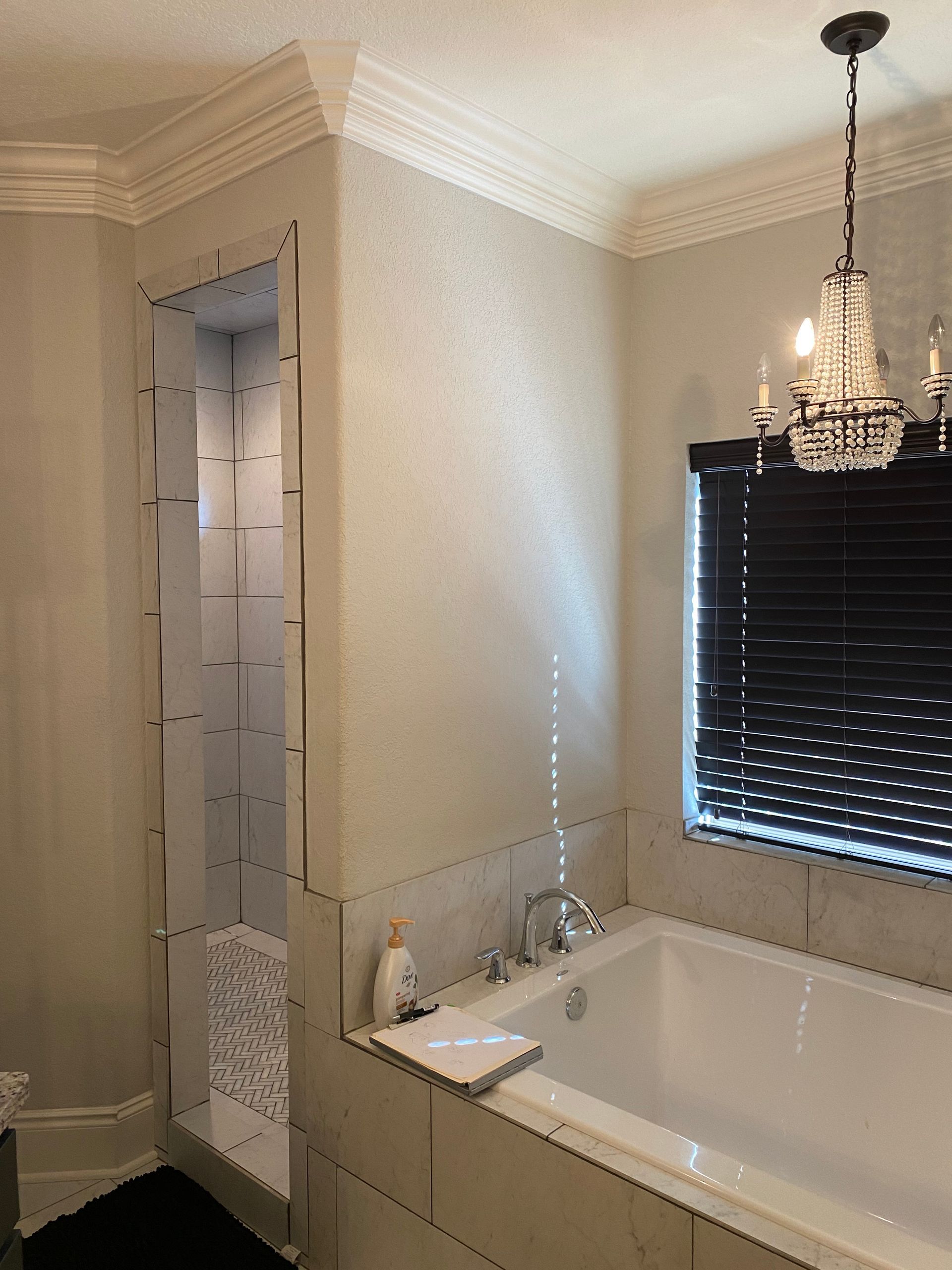 A bathroom with a bathtub and a chandelier hanging from the ceiling