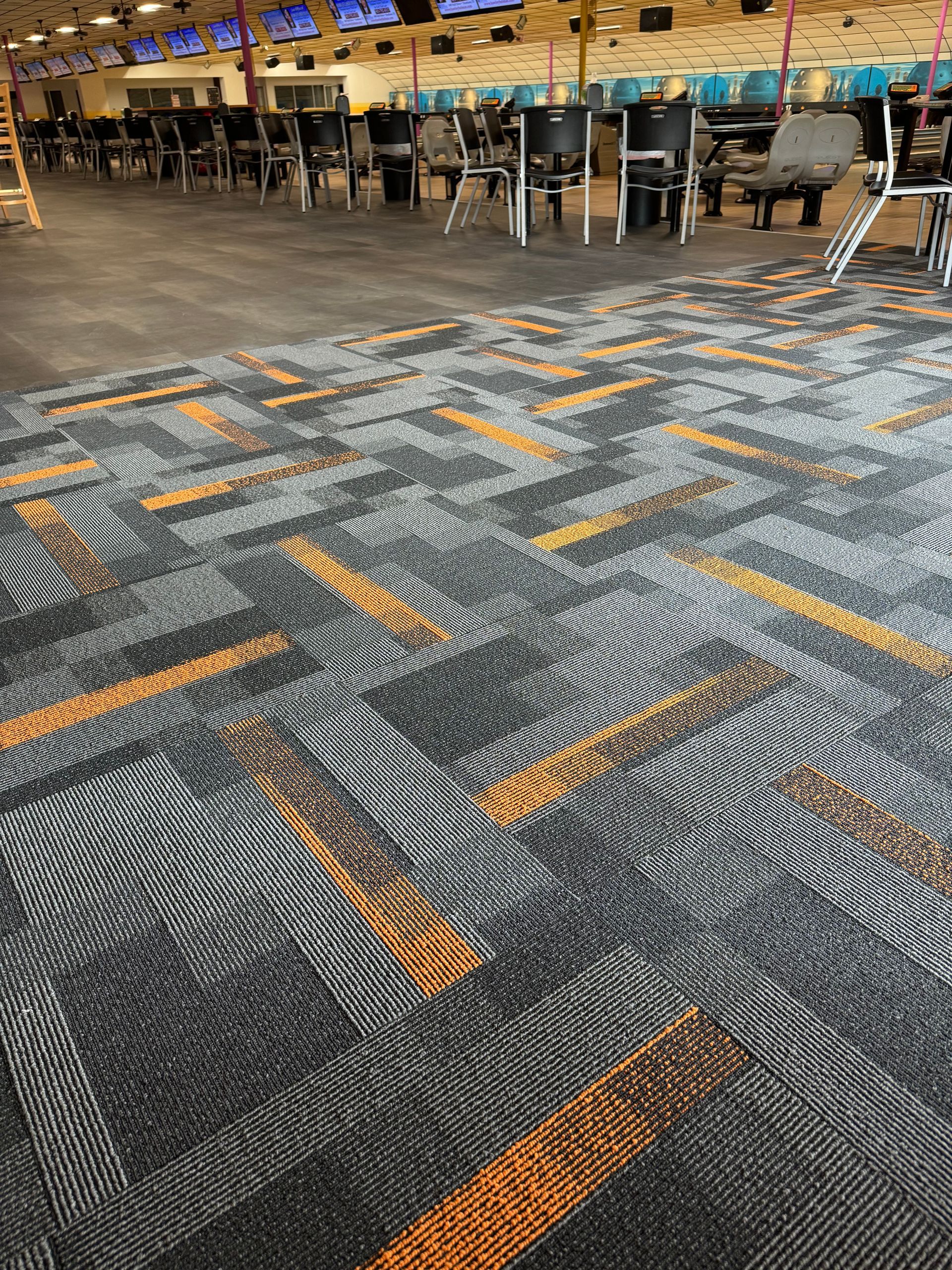 A bowling alley with a carpeted floor and chairs.