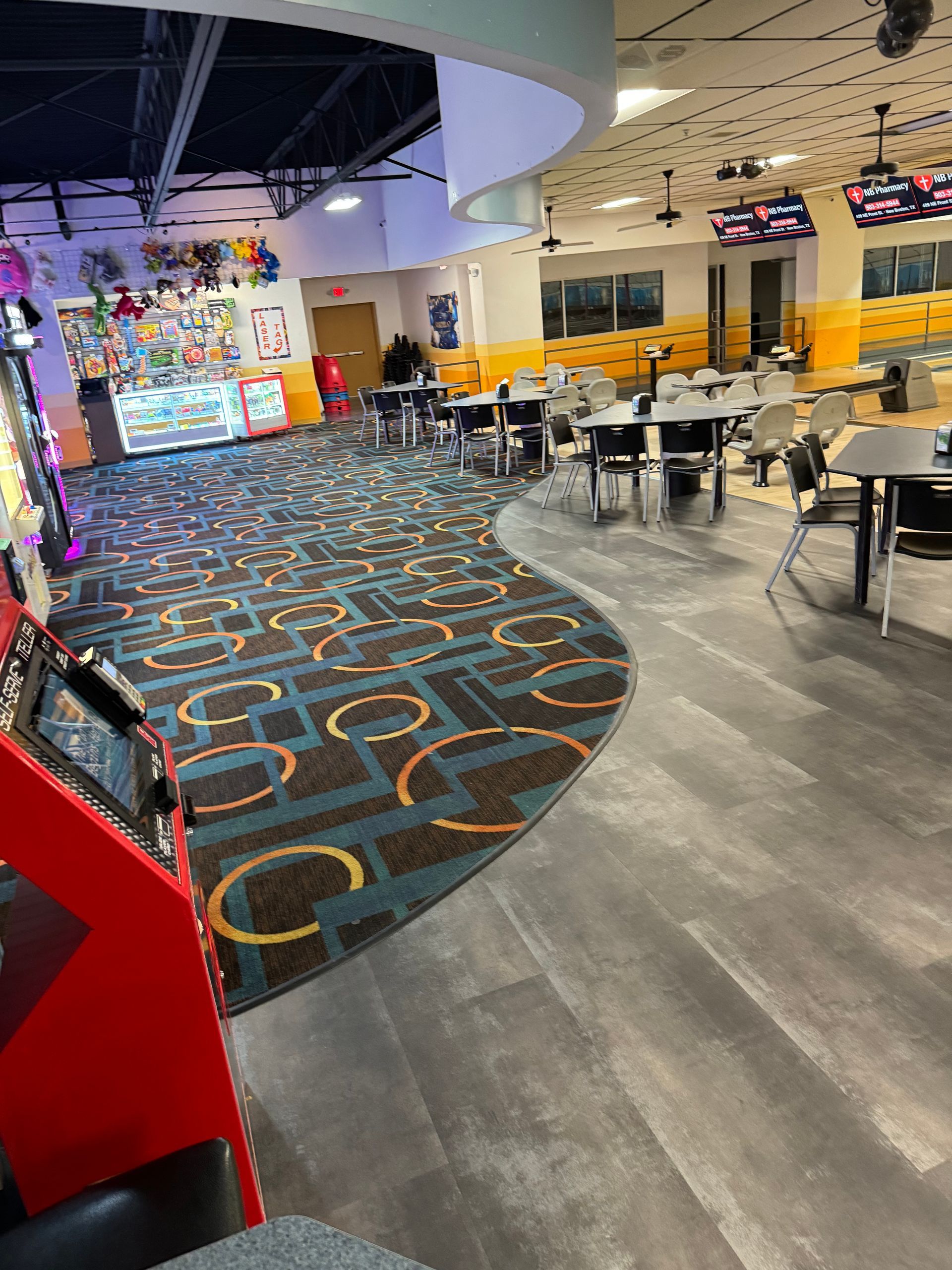 A large room with tables and chairs in a bowling alley.