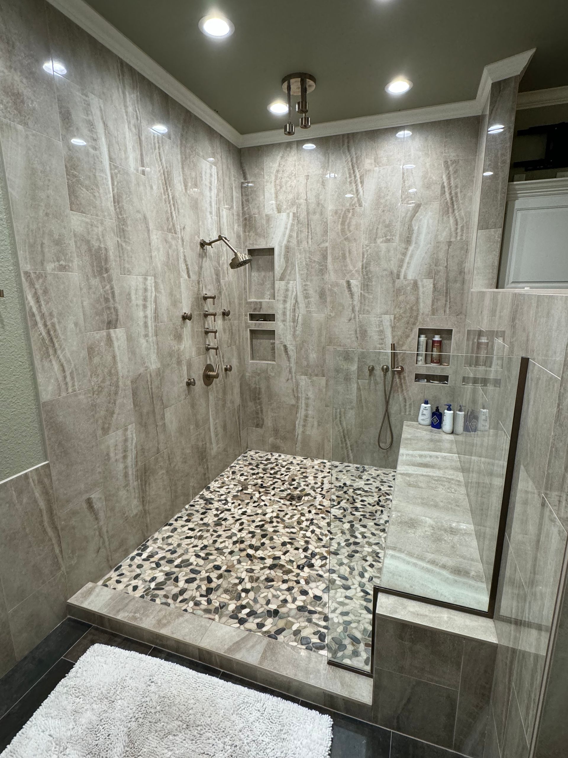 A bathroom with a walk in shower and a rug on the floor.