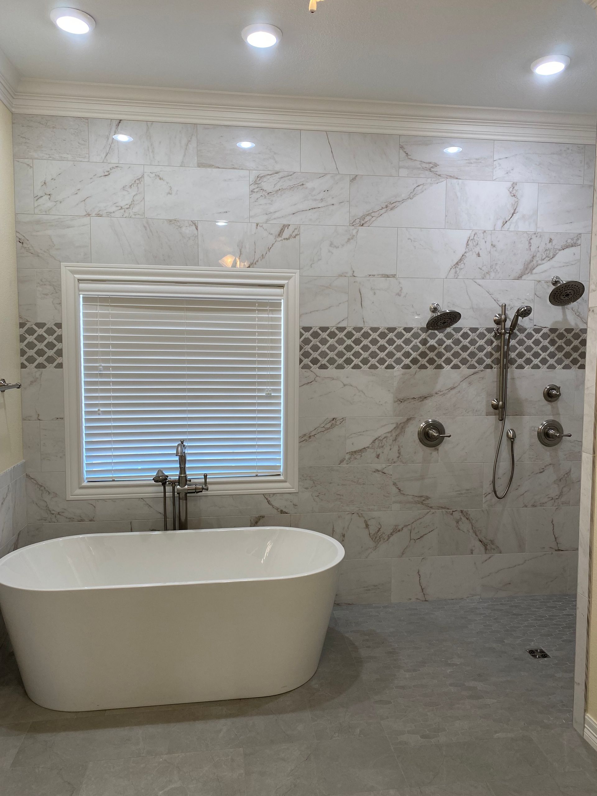 A bathroom with a tub , shower , and window.