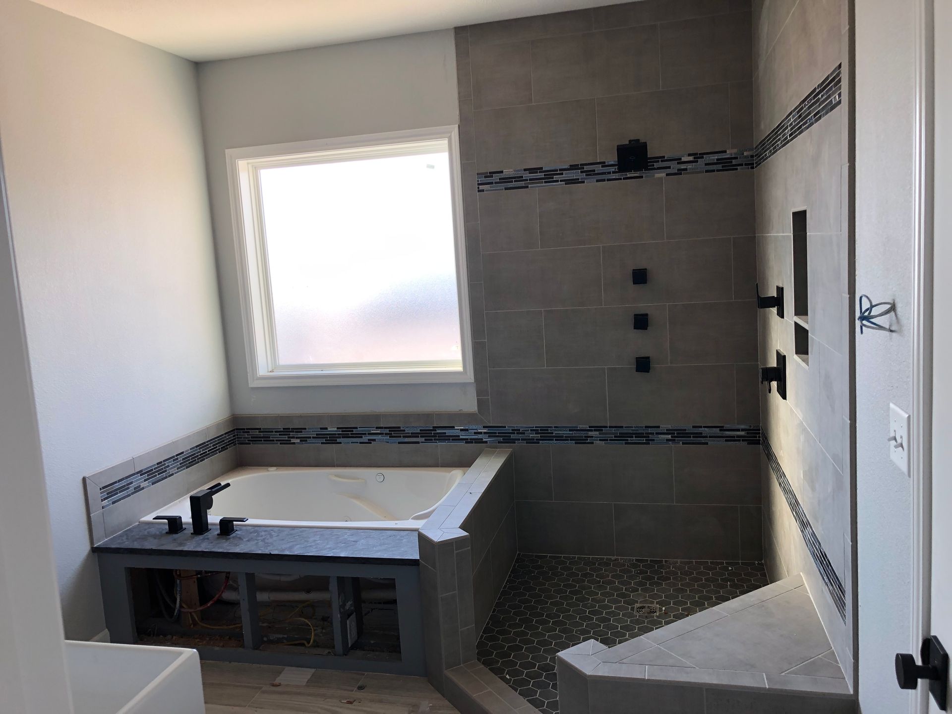 A bathroom with a tub , shower and window