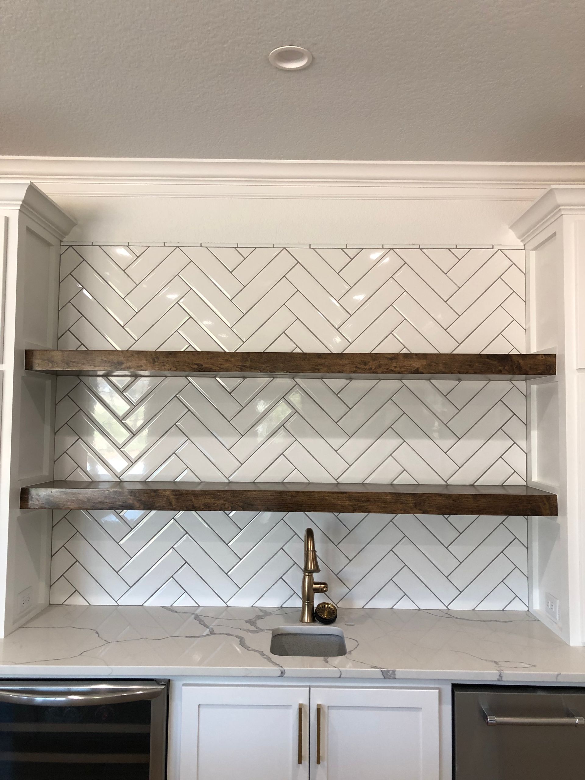 A kitchen with a sink and shelves with a herringbone pattern