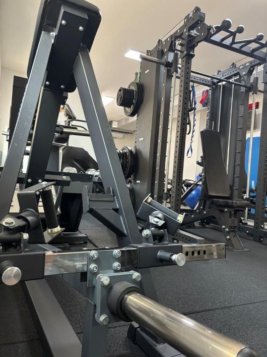 Un attrezzo per pesi nero in studio NVGYM, con uno squat rack sullo sfondo.