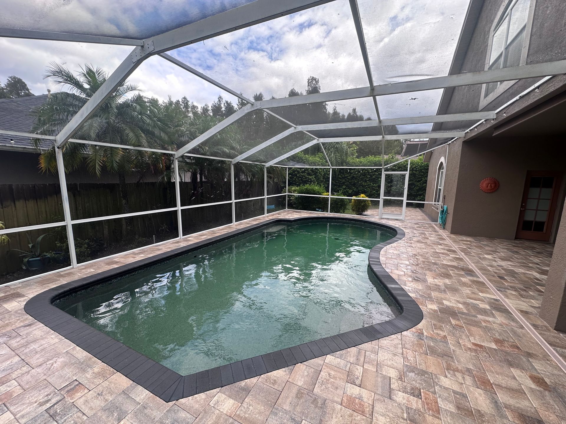 Person tiling a pool with blue square tiles, using a rubber mallet.