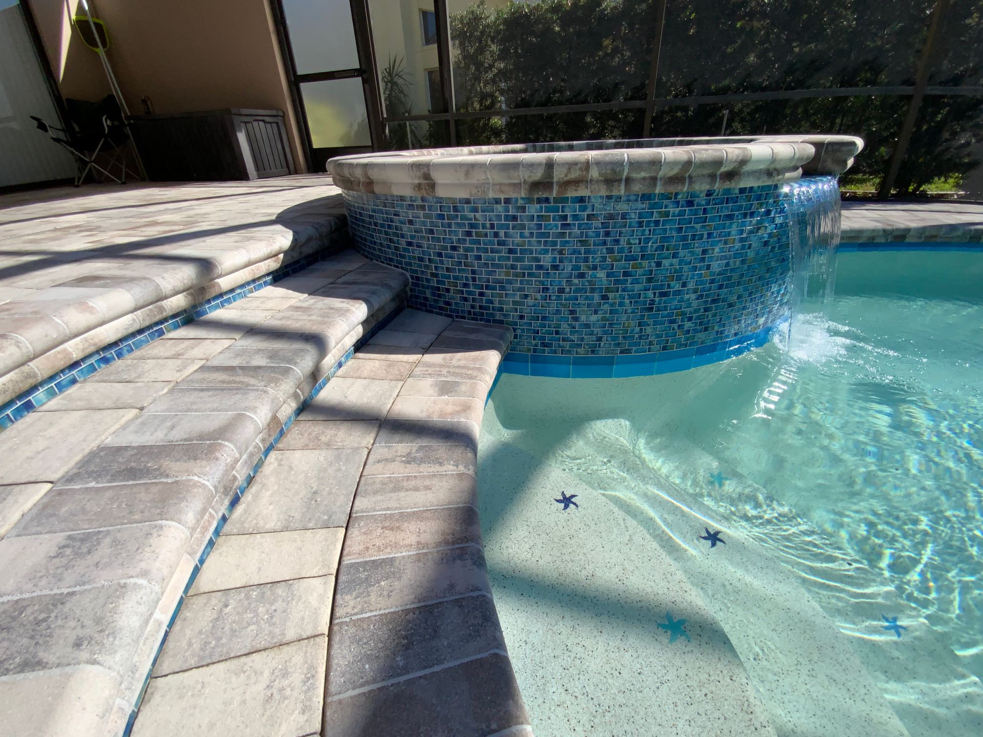 Swimming pool with blue water, concrete edge, and grass lawn.