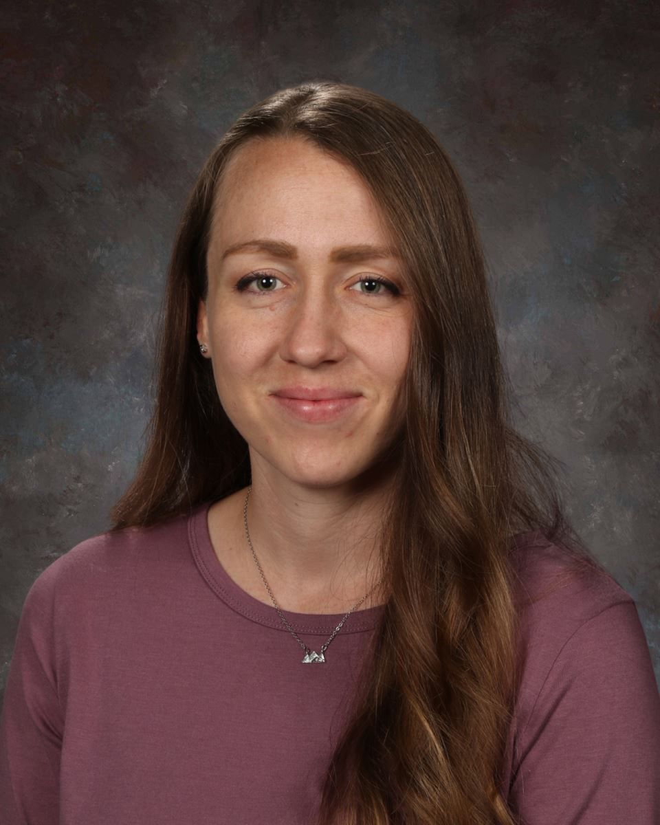 A woman in a floral shirt is smiling for a picture.
