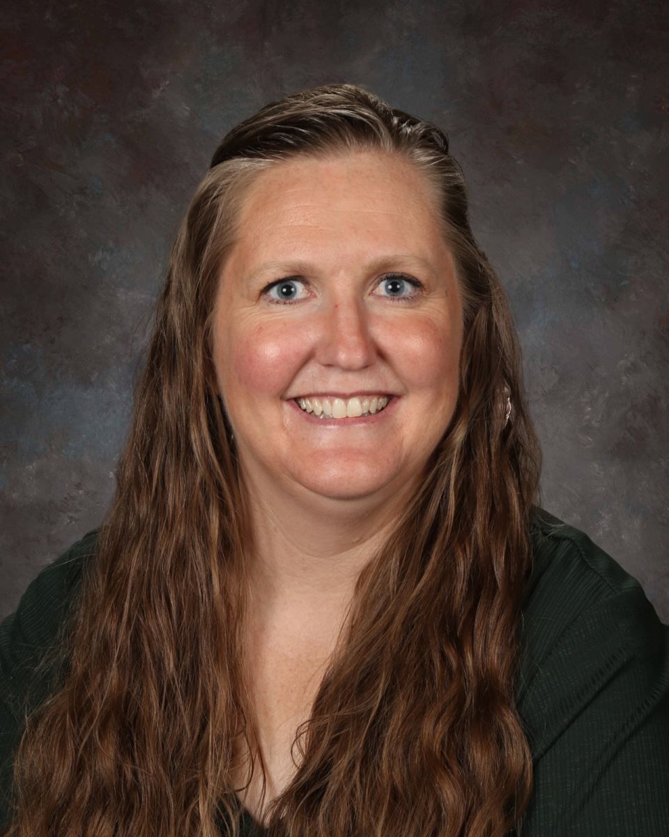 A woman with long hair is smiling for a picture.