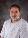 A man with a beard and mustache is wearing a white shirt.