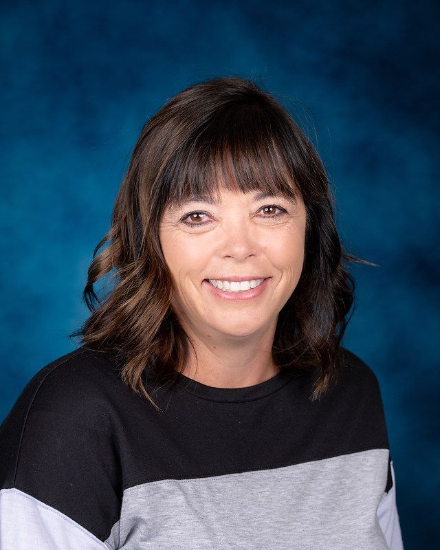 A woman is smiling for a picture in front of a blue background.