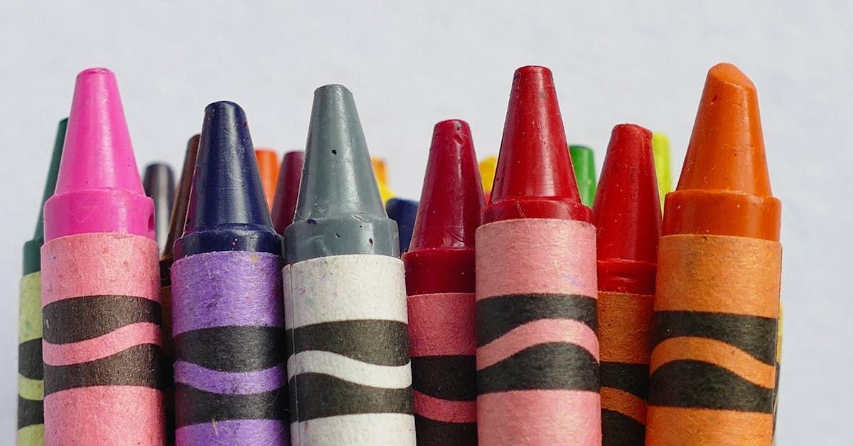 A bunch of crayons are lined up in a row on a white surface.