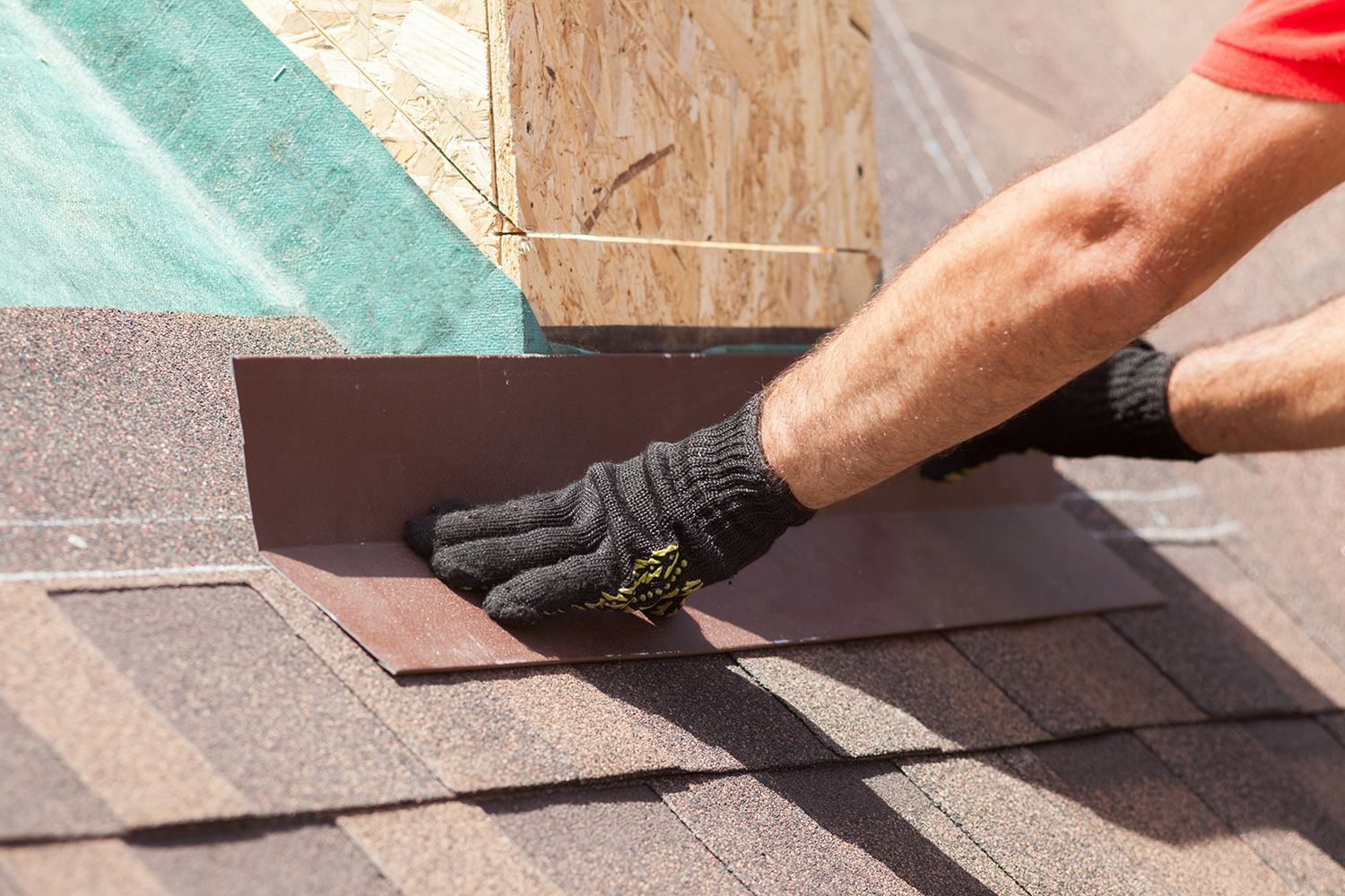 Gloved hand smoothing roofing shingles around a vent stack on a roof Gloved hand smoothing roofing shingles around a vent stack on a roof