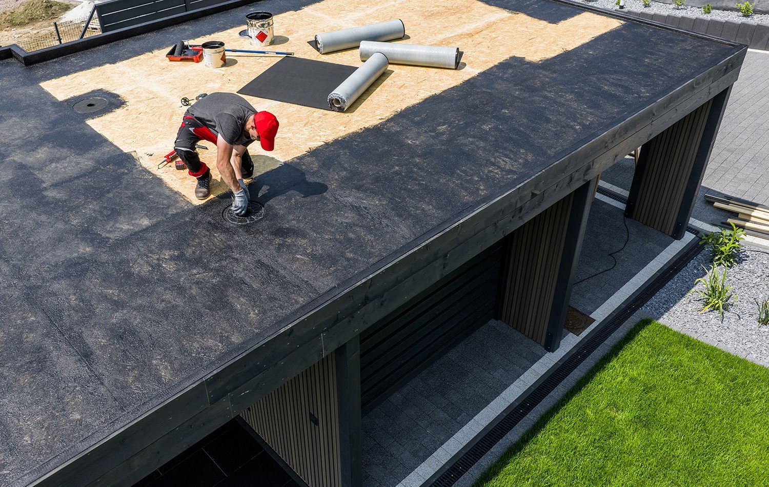 Two people on a flat roof near HVAC vents, with a grassy area beside the building Two people on a flat roof near HVAC vents, with a grassy area beside the building