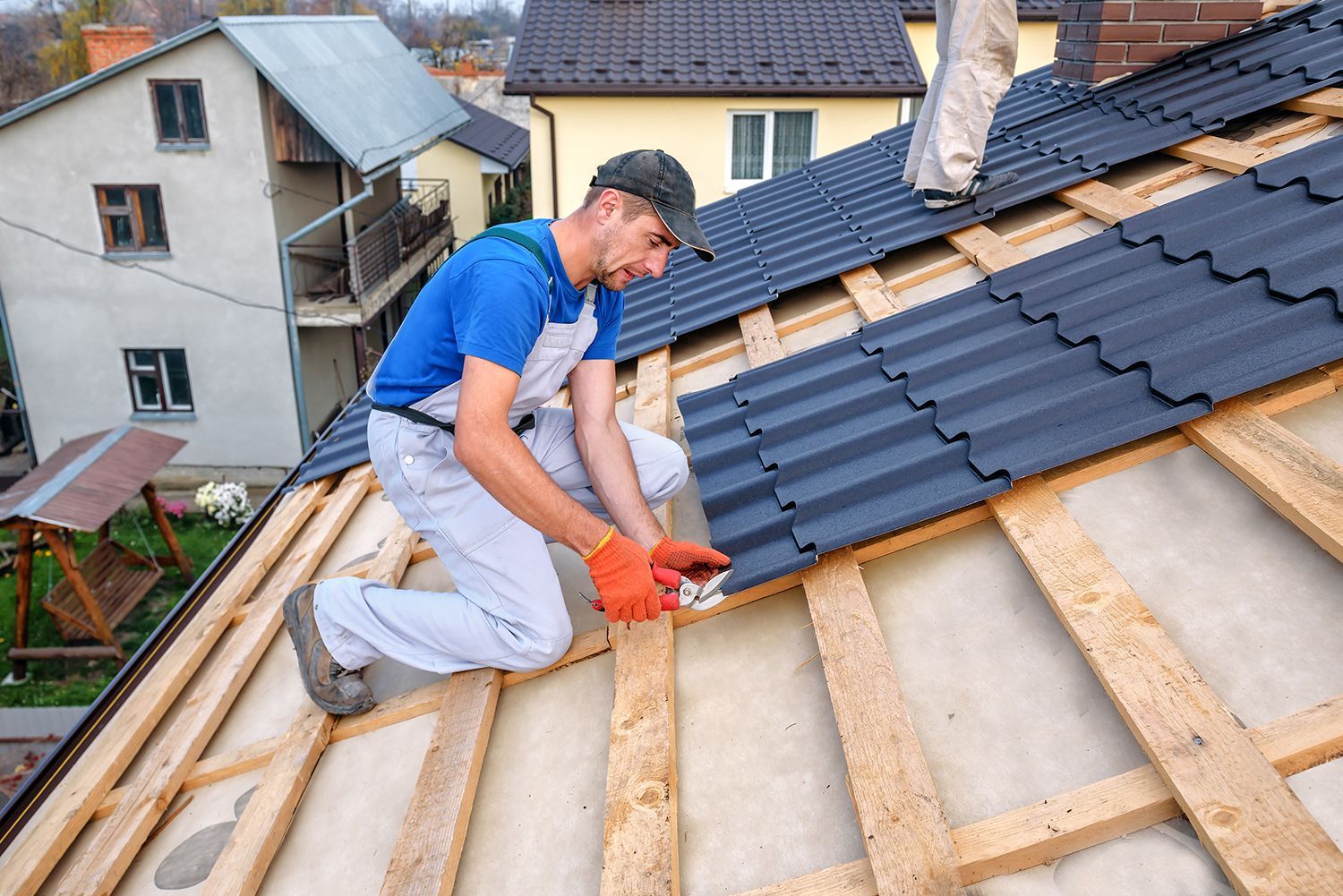 Worker installing roof shingles on a house during roof repair Worker installing roof shingles on a house during roof repair