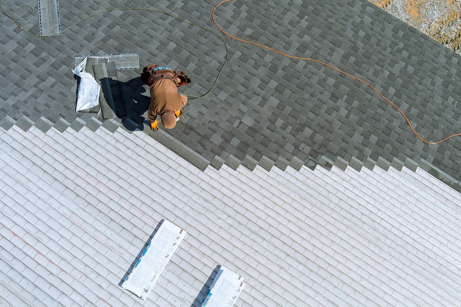 Two people and a dog on a gray rooftop beside white roof panels and an orange cord Two people and a dog on a gray rooftop beside white roof panels and an orange cord