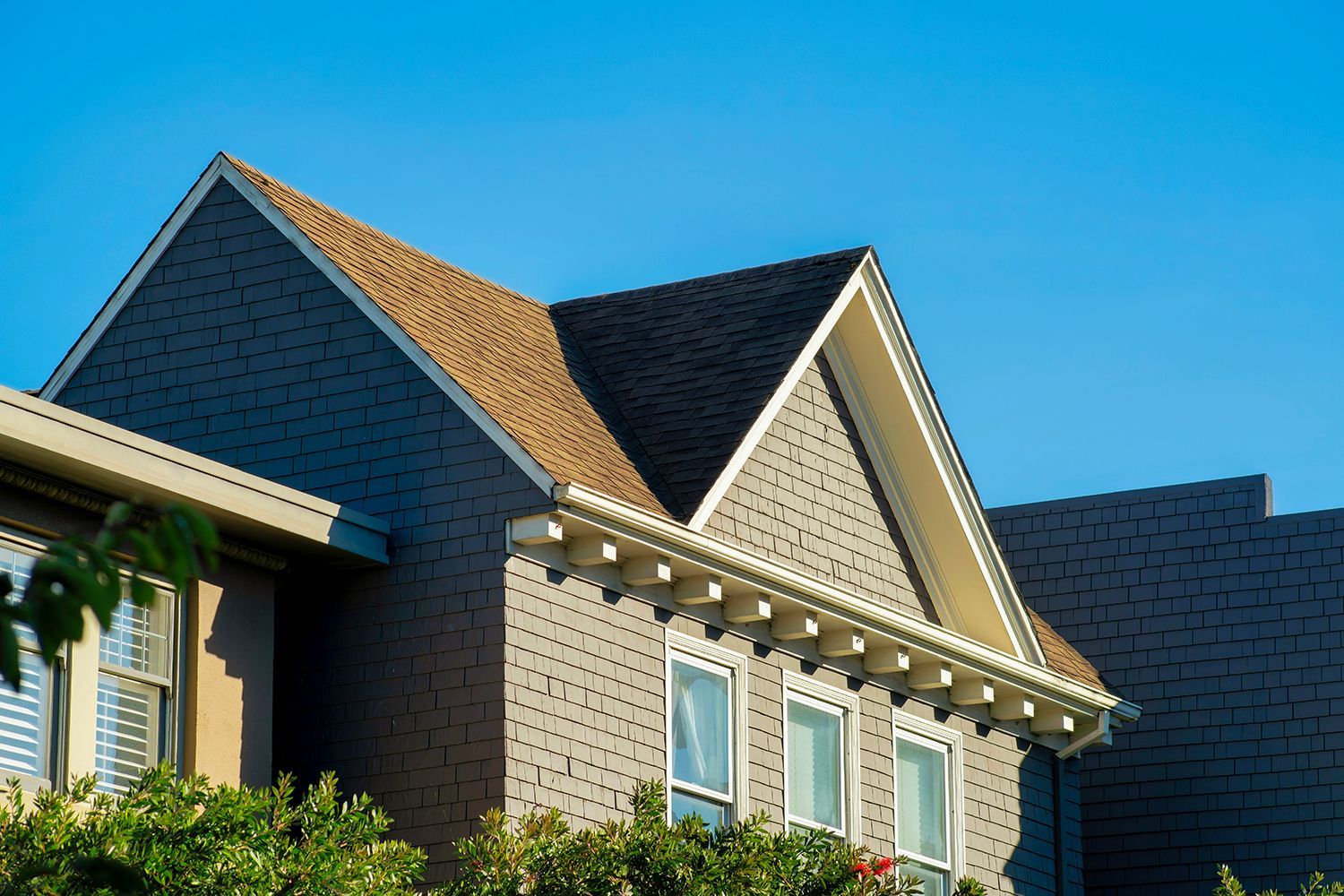 Suburban house with beige siding, steep gables, and blue sky overhead Suburban house with beige siding, steep gables, and blue sky overhead