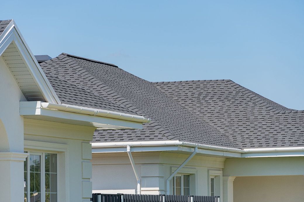 Suburban house roof and white exterior under a clear blue sky Suburban house roof and white exterior under a clear blue sky