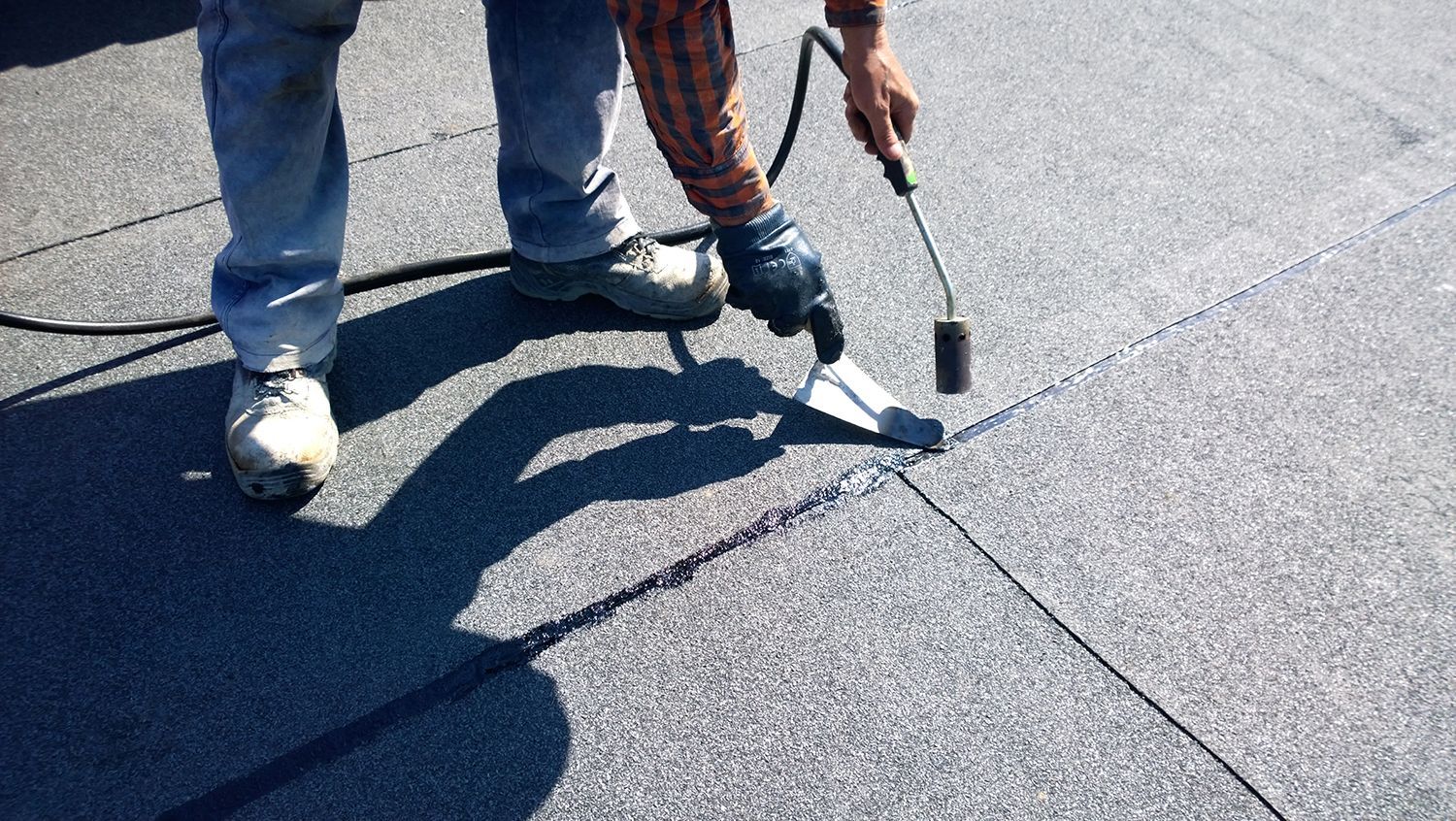 Worker inspecting a shingled roof with a hammer and pry bar Worker inspecting a shingled roof with a hammer and pry bar