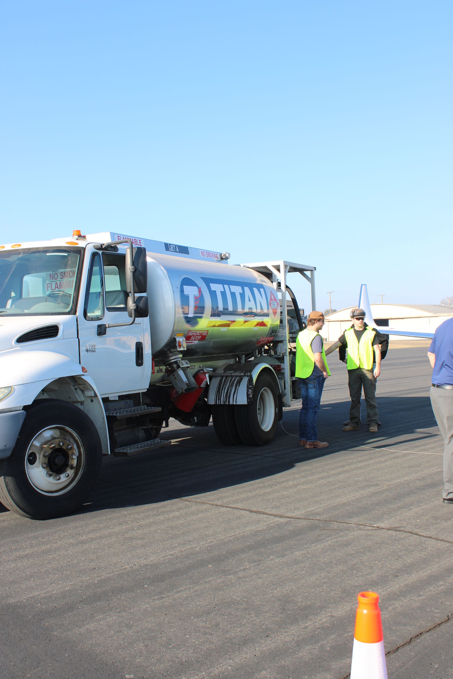 White utility truck and workers in neon vests on a roadway under a clear blue sky
