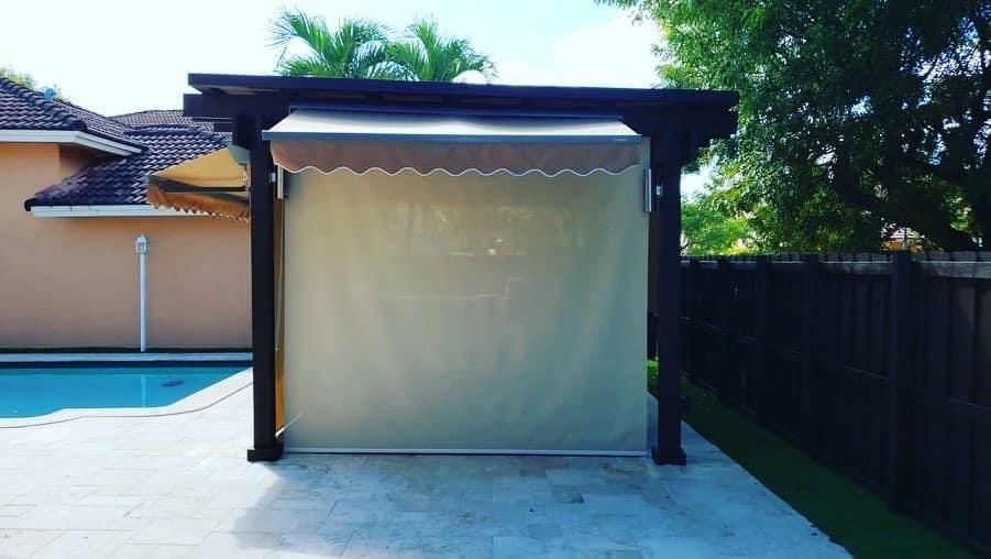 A pergola with a canopy is sitting next to a swimming pool.